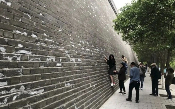 Du khách thi nhau trèo lên các bức tường thành cổ, bất chấp hành động này gây hư hại cho di tích quốc gia. Ảnh: Handout