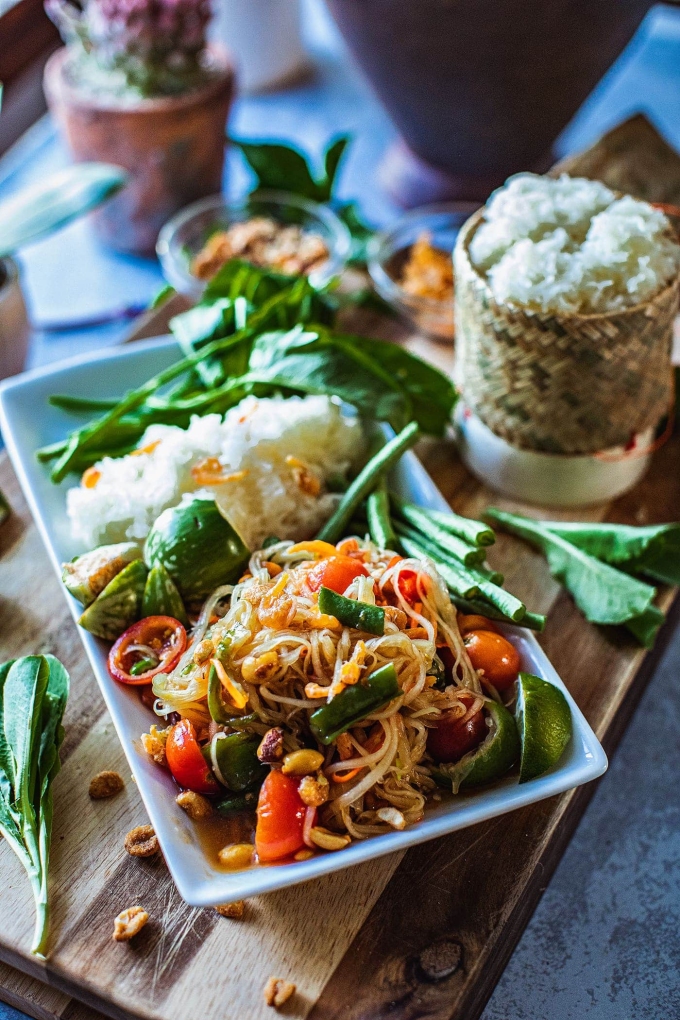 Người Thái thường ăn som tum vào mọi thời điểm trong ngày, dù là vào bữa sáng, trưa hay tối, thậm chí là bữa phụ. Gỏi đu đủ thường được ăn cùng xôi, gà nướng hay bún và rau sống. Vào 14/12/2012, som tum được Cục Xúc tiến Văn hóa Thái Lan đăng ký là món ăn di sản văn hóa phi vật thể của quốc gia. Google cũng tôn vinh món ăn này vào ngày 14/12/2021. Ảnh: Simply Suwanee