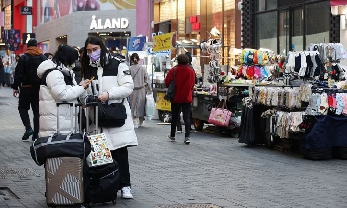 Tourists stand next to street vendors at Myeongdong shopping district in Seoul, South Korea, January 9, 2023. Photo by Reuters