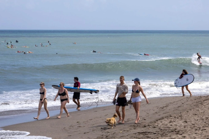 Du khách đi bộ dọc bãi biển ở Bali vào ngày 1/7. Ảnh: EPA