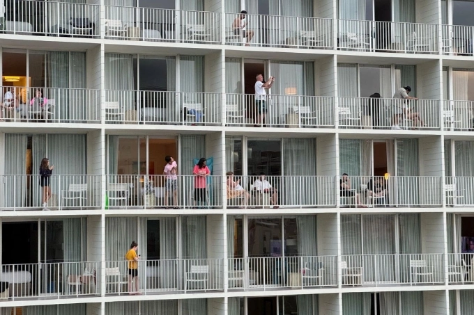 Du khách đứng trên ban công tại khu nghỉ dưỡng Alohilani nhìn về phía bãi biển Waikiki sau khi chính quyền phát cảnh báo sóng thần tại Honolulu vào hôm nay. Ảnh: Reuters