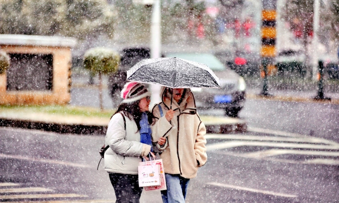 Người dân che ô đi trong tuyết giữa mùa thu tại Cáp Nhĩ Tân, tỉnh Hắc Long Giang, ngày 19/10. Ảnh: IC