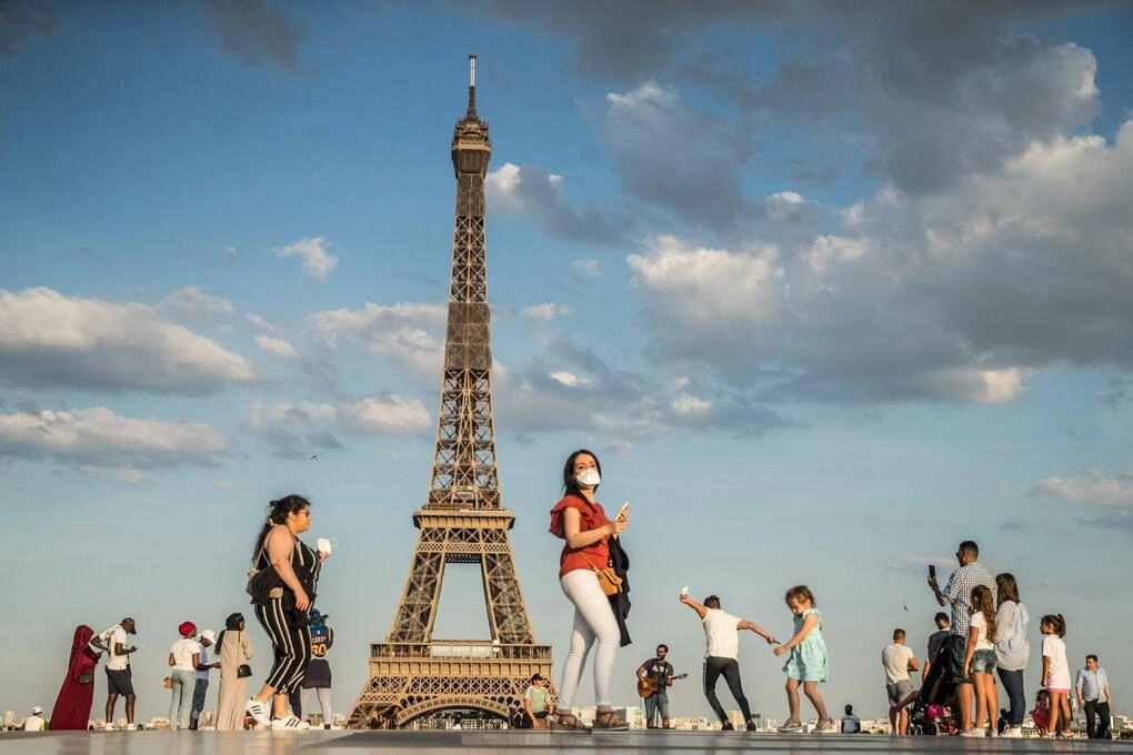 Du khách đi bộ ngay dưới chân tháp Eiffel. Ảnh: Reuters